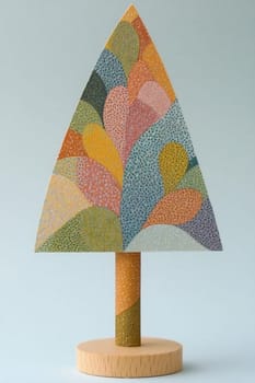 A vibrant wooden tree sculpture stands on a light backdrop, adorned with intricate colors and shapes, emphasizing a playful design.