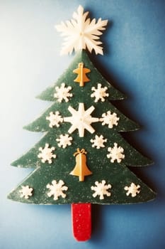 A creatively designed Christmas tree showcases festive decorations like snowflakes and bells set against a vibrant blue backdrop.