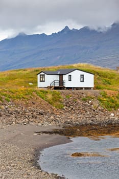 White Siding House at coastlineÊin East Iceland. Vertical shot