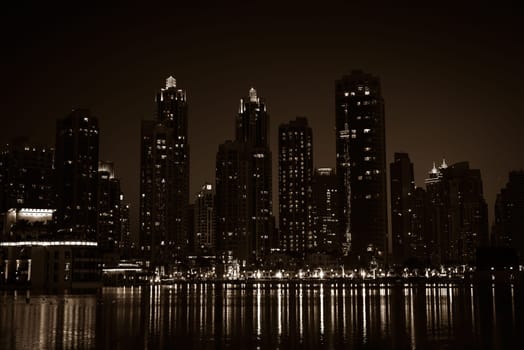 Night cityscape of Dubai city, United Arab Emirates. Reflections in the water. Sepia toned shot