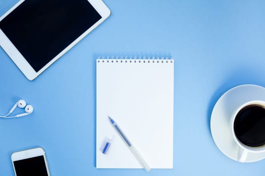 Creative flat lay photo of workspace desk with paper notebook, smartphone, earpieces, pen and coffee with copy space background minimal style