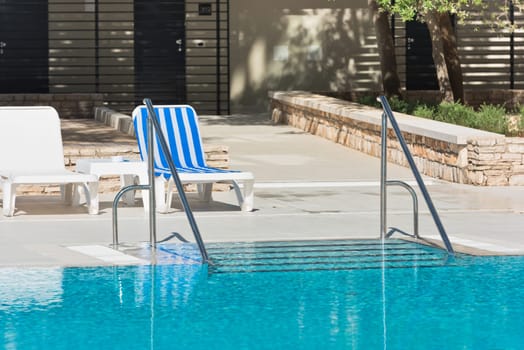 Hotel Poolside Chairs near a swimming pool. Summer shot