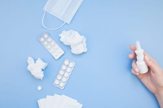 Creative flat lay concept of seasonal spring allergy with napkins, pills, face mask, drops in a bottle and a female hand with copy space background minimal style, template for text