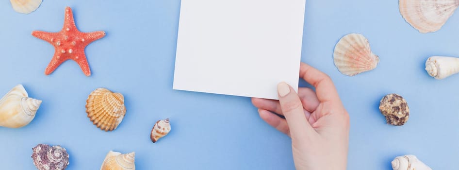 Creative long wide banner flat lay concept of summer travel vacations. Top view of seashells and starfish on pastel blue background with postcard mock up and copy space in minimal style, template