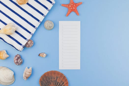Creative flat lay concept of summer travel vacations. Top view of beach towel and seashells and starfish on pastel blue background with copy space in minimal style, template for text