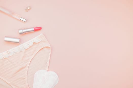 Feminine flat lay set of female panties and accessories, perfumes, lipstick, earrings and pads liners on pastel pink color background for fashion blog and social media with copy space for text