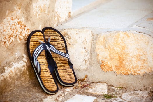 Beach flip-flops on the old wall background. Horizontal shot