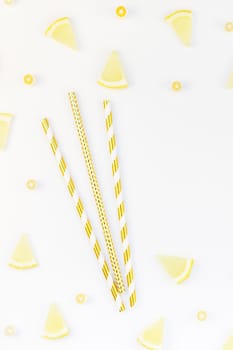 Creative flatlay overhead top view citrus lemon slices pattern frame white table background with copyspace. Hot summer refreshment lemonade concept. Beverage ingredients arranged straws and candies
