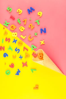 Creative flat lay back to school concept with waffle cone and welcome letters message on bright yellow and pink paper background with copy space, template for text or design