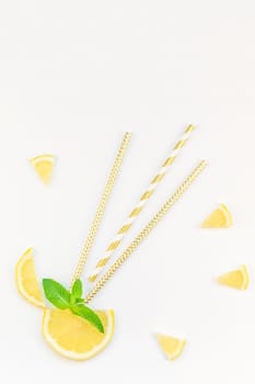 Creative flatlay overhead top view citrus lemon slices and mint herbs leaves white table background with copyspace. Hot summer refreshment lemonade concept. Beverage ingredients arranged with straws