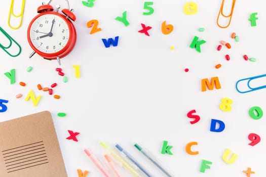 Creative flat lay back to school concept with alarm clock, color school and office supplies on white table background with copy space, frame, template for text or design