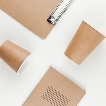 Square top view flat lay of workspace desk styled recycled brown design office supplies and coffee cups with copy space white table background minimal eco style. Concept of environmental protection