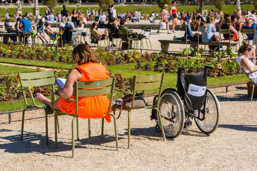 FRANCE, PARIS - JUNE 06: Woman sitting on a chair in the park and reading a book on June 06, 2015.
