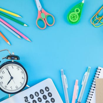 Square Creative flat lay top view back to school concept with alarm clock color school and office supplies on bright turquoise paper table frame background with copy space, template for text or design