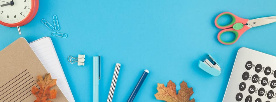 Creative flat lay top view back to school concept with color school and office supplies on bright turquoise paper table frame background with copy space, template for text or design. Long wide banner