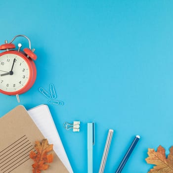 Square Creative flat lay top view back to school concept with alarm clock color school and office supplies on bright turquoise paper table frame background with copy space, template for text or design