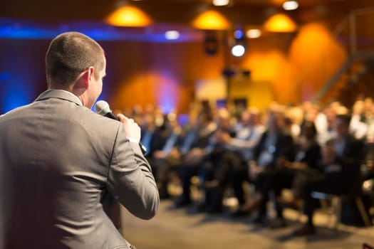 Speaker giving a talk on corporate business conference. Unrecognizable people in audience at conference hall. Business and Entrepreneurship event.
