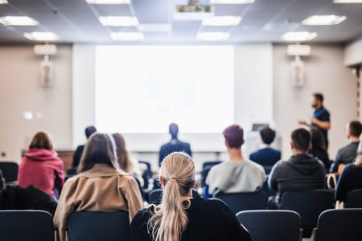 Speaker giving a talk in conference hall at business event. Rear view of unrecognizable people in audience at the conference hall. Business and entrepreneurship concept