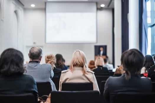 Speaker giving a talk in conference hall at business event. Rear view of unrecognizable people in audience at the conference hall. Business and entrepreneurship concept