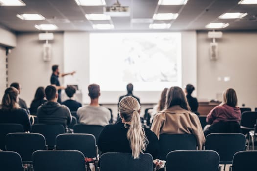 Speaker giving a talk in conference hall at business event. Rear view of unrecognizable people in audience at the conference hall. Business and entrepreneurship concept