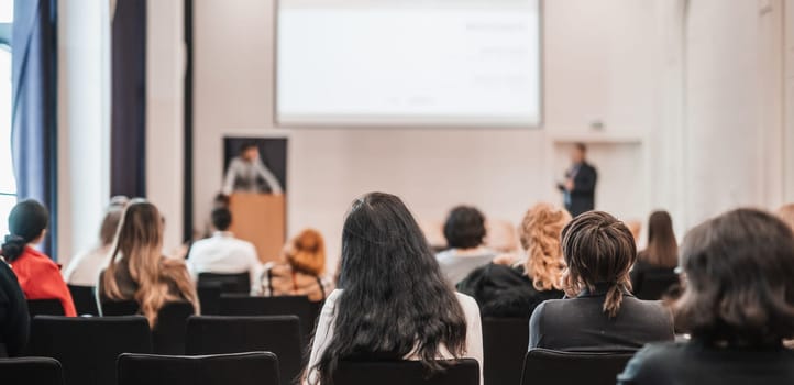 Speaker giving a talk in conference hall at business event. Rear view of unrecognizable people in audience at the conference hall. Business and entrepreneurship concept