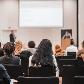 Speaker giving a talk in conference hall at business event. Rear view of unrecognizable people in audience at the conference hall. Business and entrepreneurship concept