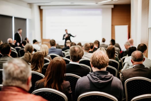 Speaker giving a talk in conference hall at business event. Rear view of unrecognizable people in audience at the conference hall. Business and entrepreneurship concept