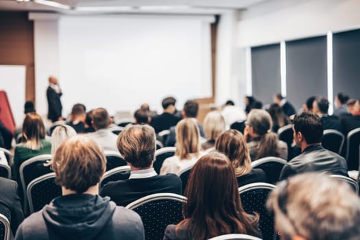 Speaker giving a talk in conference hall at business event. Rear view of unrecognizable people in audience at the conference hall. Business and entrepreneurship concept