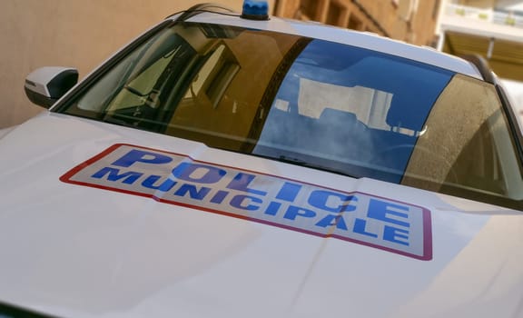 A police car with a blue and red sign on the hood. The sign says Police Municipal. The car is parked on the side of the road