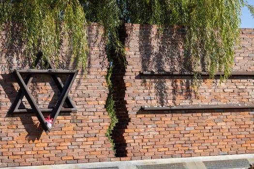 Czestochowa, Poland - October 18, 2024: Monument to Jews of Czestochowa, commemorates 40,000 Jews murdered in the Treblinka death camp. Star of David made of railway rails, crack in red brick wall