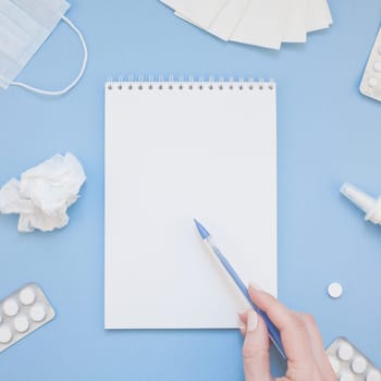Creative flat lay concept of seasonal spring allergy with napkins, pills, face mask, drops in a bottle and a female hand with square copy space background minimal style, template for text