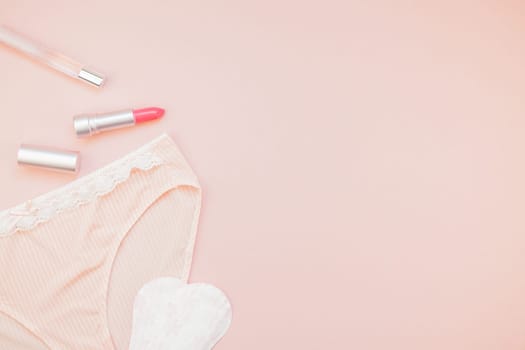 Feminine flat lay set of female panties and accessories, perfumes, lipstick and pads liners on pastel pink color background for fashion blog and social media with copy space for text