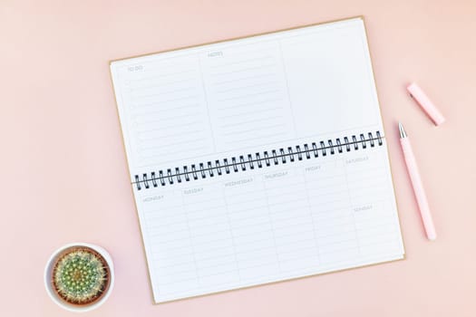 Top view flat lay of workspace desk styled design office supplies and cactuses succulents with copy space millennial pink color paper background minimal style. Template for feminine blog social media