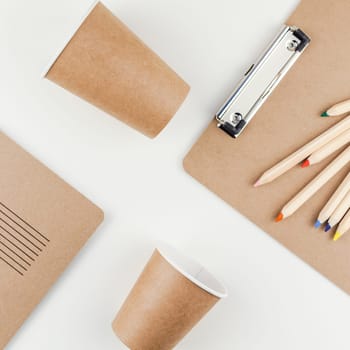 Square top view flat lay of workspace desk styled recycled brown design office supplies and coffee cups with copy space white table background minimal eco style. Concept of environmental protection