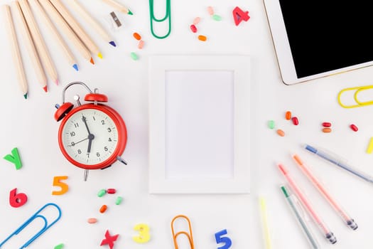 Creative flat lay back to school concept blank tablet with alarm clock, color school and office supplies on white table background with copy space, frame, template for text or design