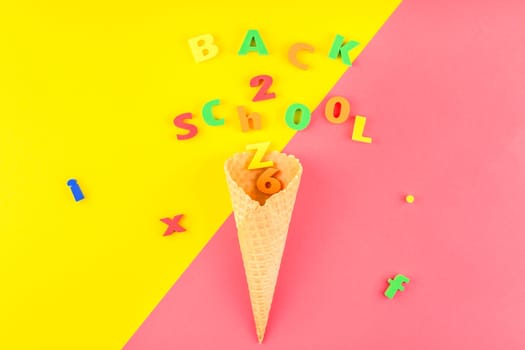 Creative flat lay back to school concept with waffle cone and welcome letters message on bright yellow and pink paper background with copy space, template for text or design