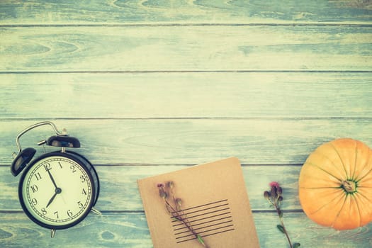 Top view of autumn orange pumpkins and dry flowers and grass in box thanksgiving background over blue toned wooden table with copy space. Template for fall harvest mood text