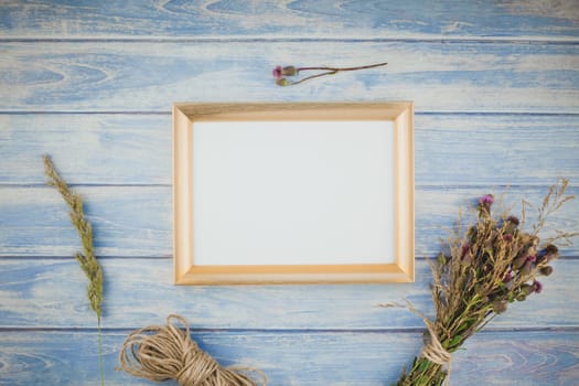 Top view of autumn orange pumpkins and dry flowers with grass thanksgiving background over blue toned wooden table with golden frame mock up and copy space in rustic style, template for text