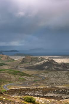 Highway through Iceland landscape at overcast day with rainbow. Vertical shot