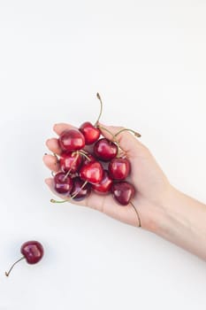 Creative top view of fresh ripe cherry in a female hands with copy space isolated on white background in minimal style. Concept of summer fun and healthy eating. Template for your text or food design