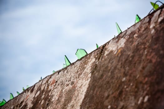 Cement wall covered with broken glass pieces. Shot with a selective focus