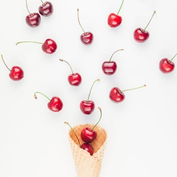 Square Creative top view of ripe cherries in a waffle cone with copy space isolated on white background in minimal style. Concept of summer fun and healthy eating. Template for your text or design.