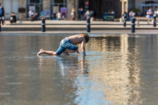 FRANCE, BORDEAUX - SEPTEMBER 20: People having fun in a mirror fountain in front of Place de la Bourse in Bordeaux, France on September 20, 2015
