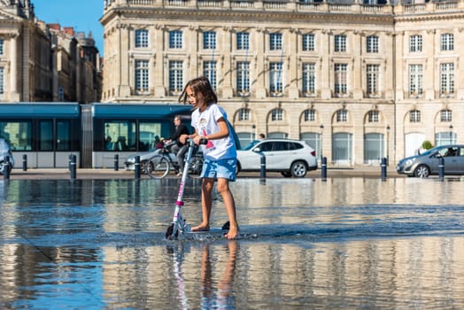 FRANCE, BORDEAUX - SEPTEMBER 20: People having fun in a mirror fountain in front of Place de la Bourse in Bordeaux, France on September 20, 2015