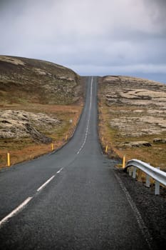Highway through Iceland Mountain landscape at overcast day. Vertical shot