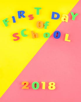 Creative flat lay back to school concept with welcome letters message on bright yellow and pink paper background with copy space, template for text or design