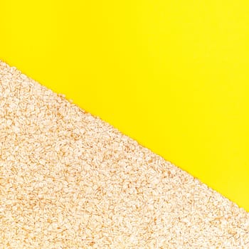 Creative flat lay concept top view of oatmeal flakes for healthy and vegetarian organic food for breakfast on a bright yellow color paper background with copy space in minimal style, square template