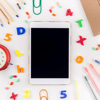 Square flat lay back to school concept blank tablet with alarm clock, color school and office supplies on white table background with copy space, frame, template for text or design