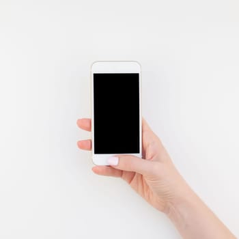 Woman hand with pastel manicure polish holding smartphone isolated on white background with copy space in minimalism style. Square Template mock up for feminine blog social technological media