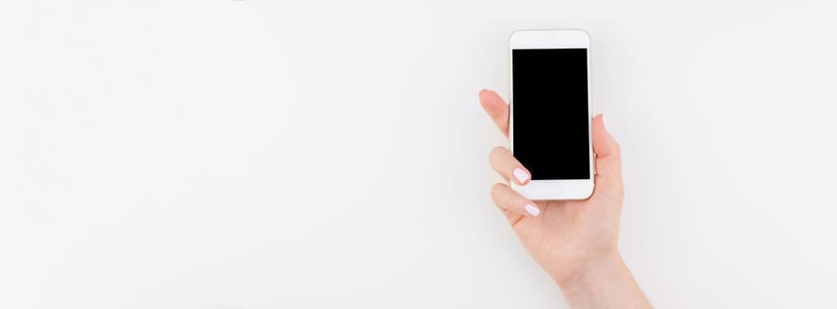 Woman hand with pastel manicure polish holding smartphone isolated on white background with copy space in minimalism style. Long wide banner mock up for feminine blog social technological media